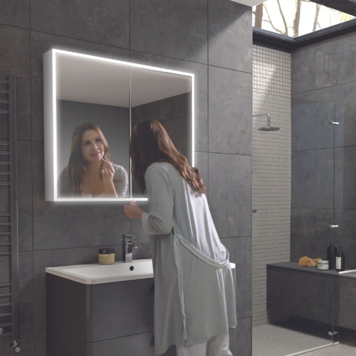 Product Lifestyle image of a woman checking her reflection in the HIB Qubic 800mm LED Mirror Cabinet